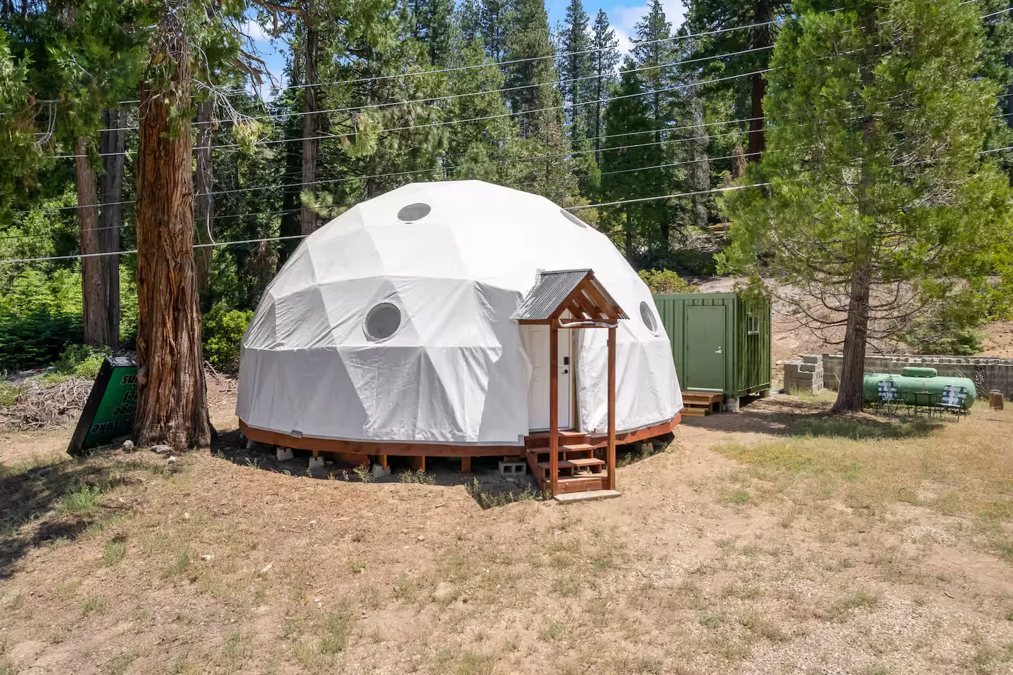 Full exterior view of the white dome surrounded by forest
