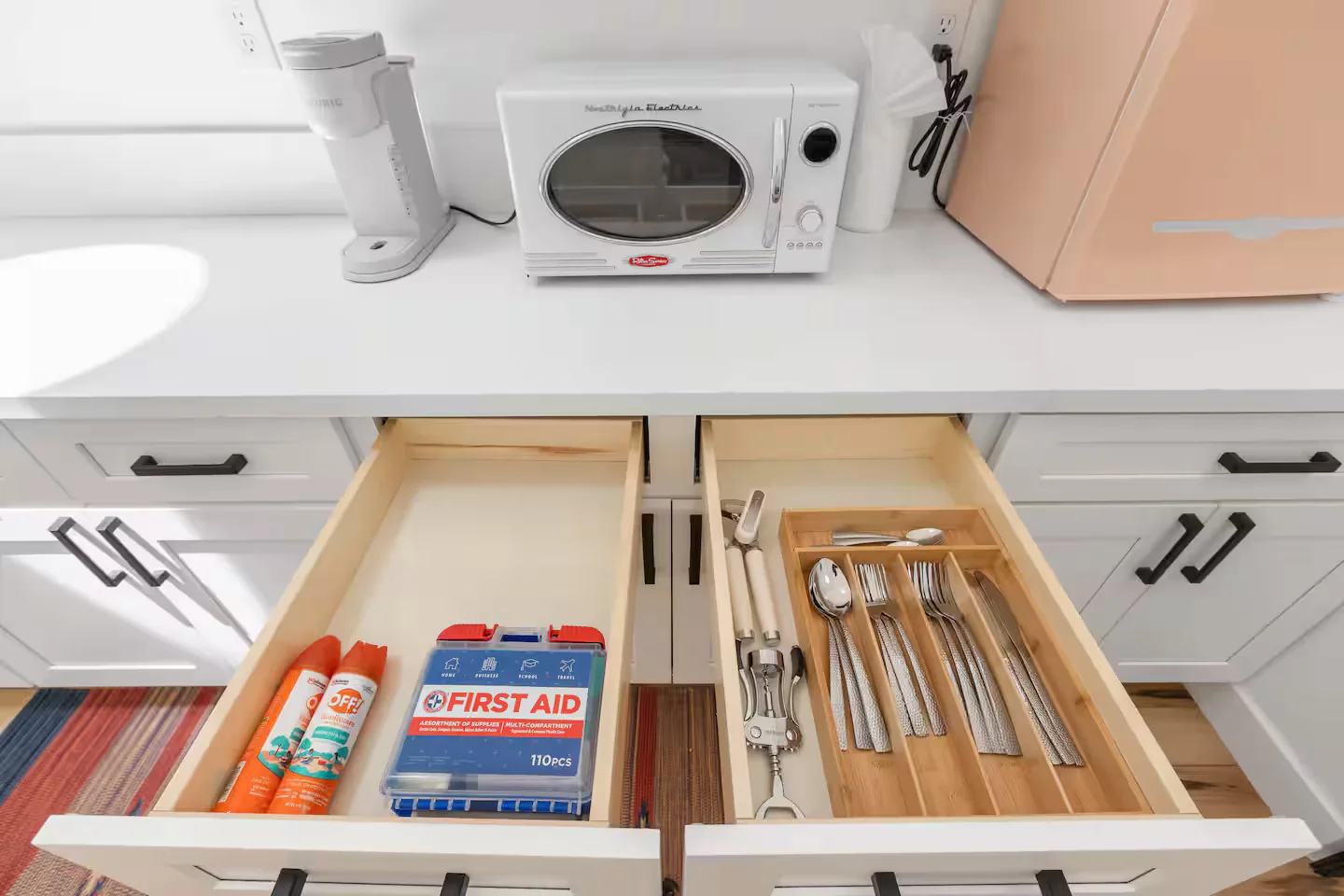 Open kitchenette drawers with utensils and supplies